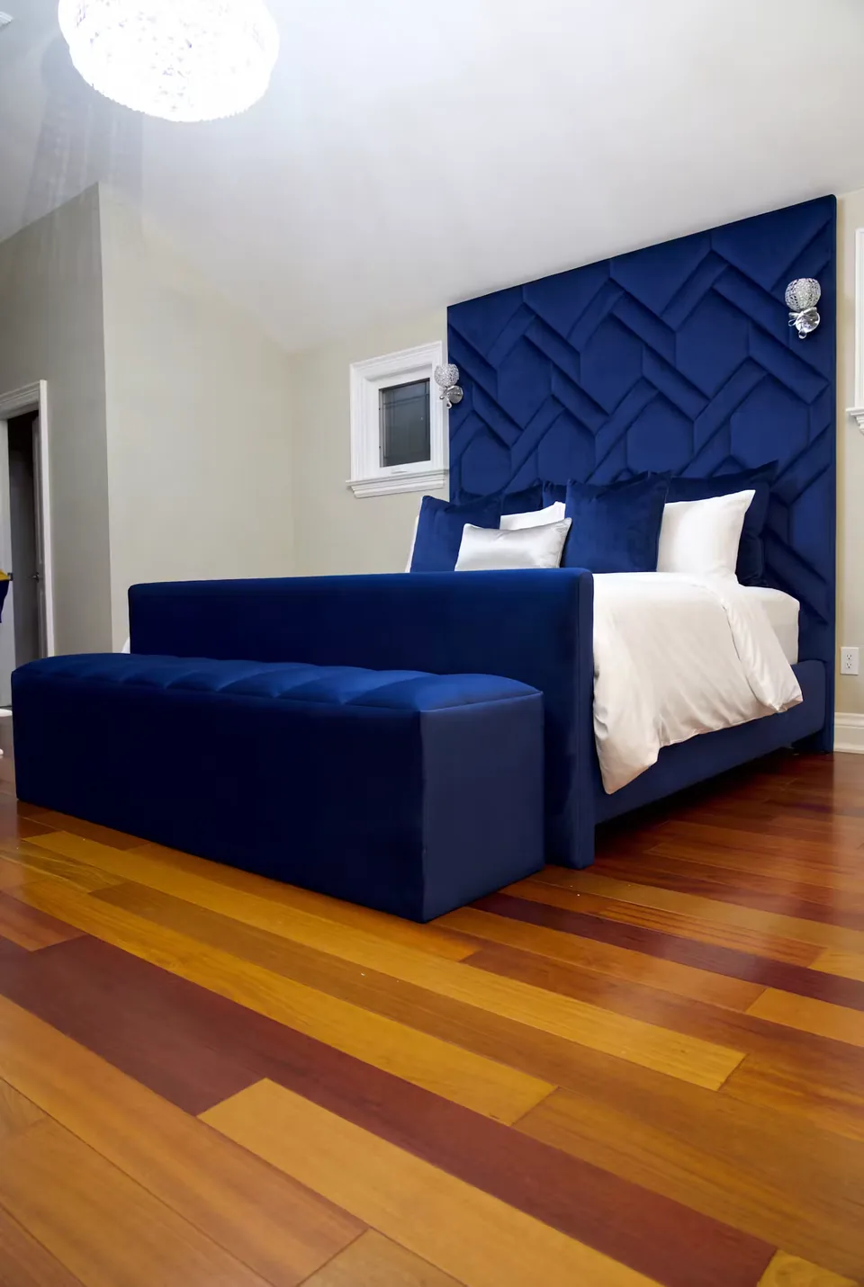 Angled view of the deep blue bed, bench and layered diagonal headboard