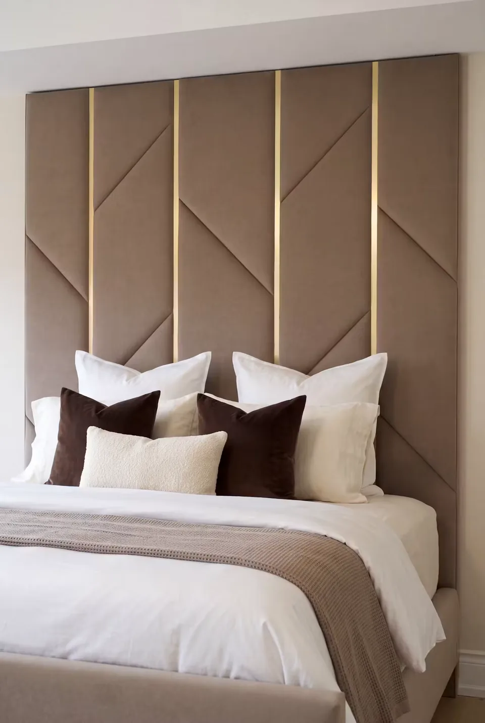 Close view of cocoa panels, diagonal seams and gold divisions above white and brown pillows.