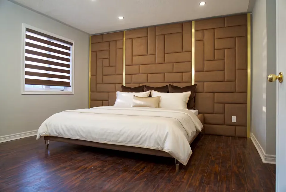 Full room view of the pale bed beneath the cocoa rectangular panel wall