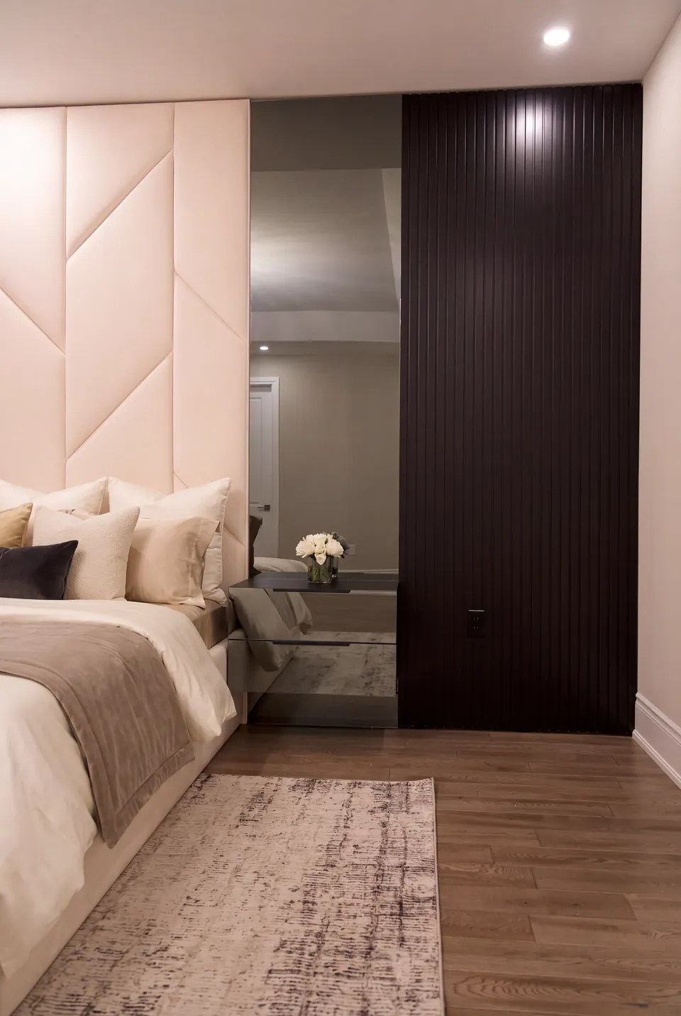 Side view of cream wall panels, a mirrored bedside area and dark vertical slats.