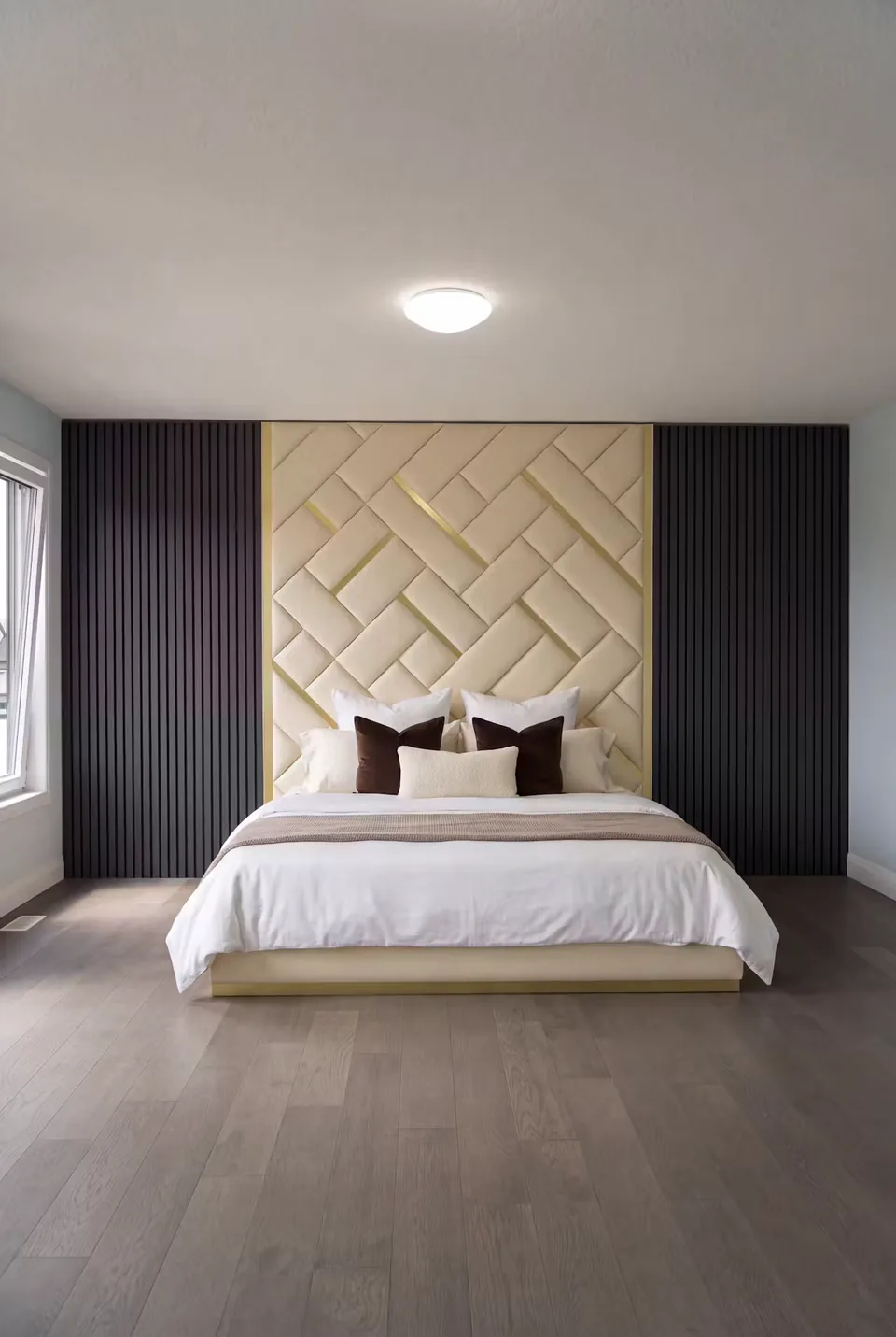 Full front view of the low cream bed and basketweave headboard framed by dark slats.