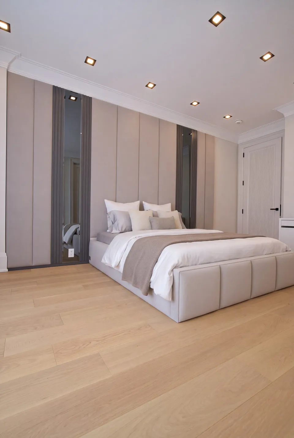 Full angled view of the cream bed beside a large curtained window.