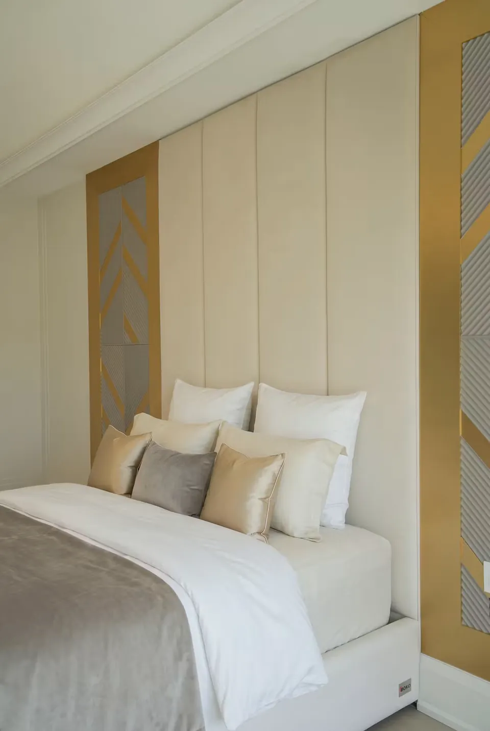 Close view of cream pillows and a gold-lined grey side panel.