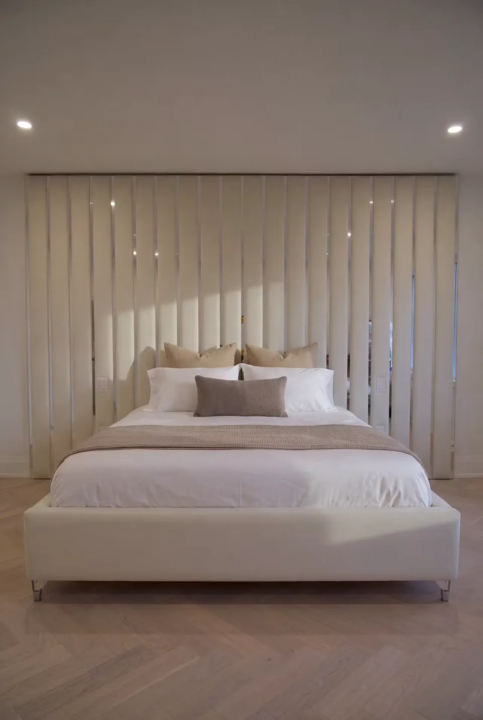 Cream upholstered bed beneath tall panels with slim mirror accents