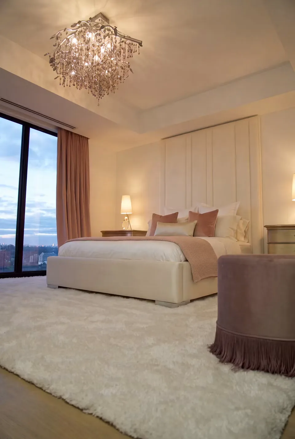 Cream upholstered bed with broad vertical headboard panels beside long curtains