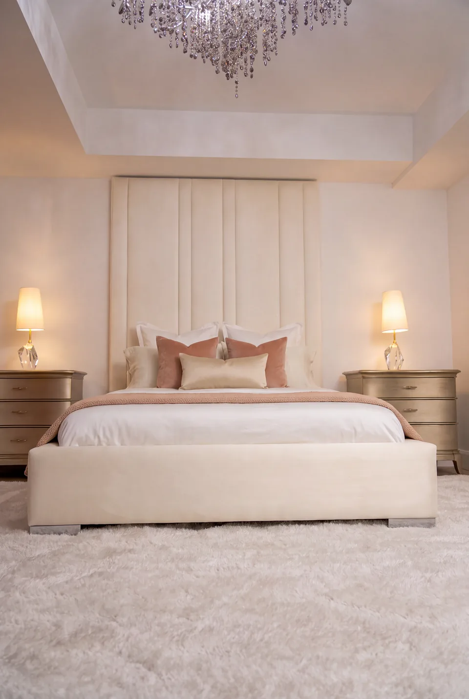 Full view of the cream column headboard and matching bed between two bedside lamps