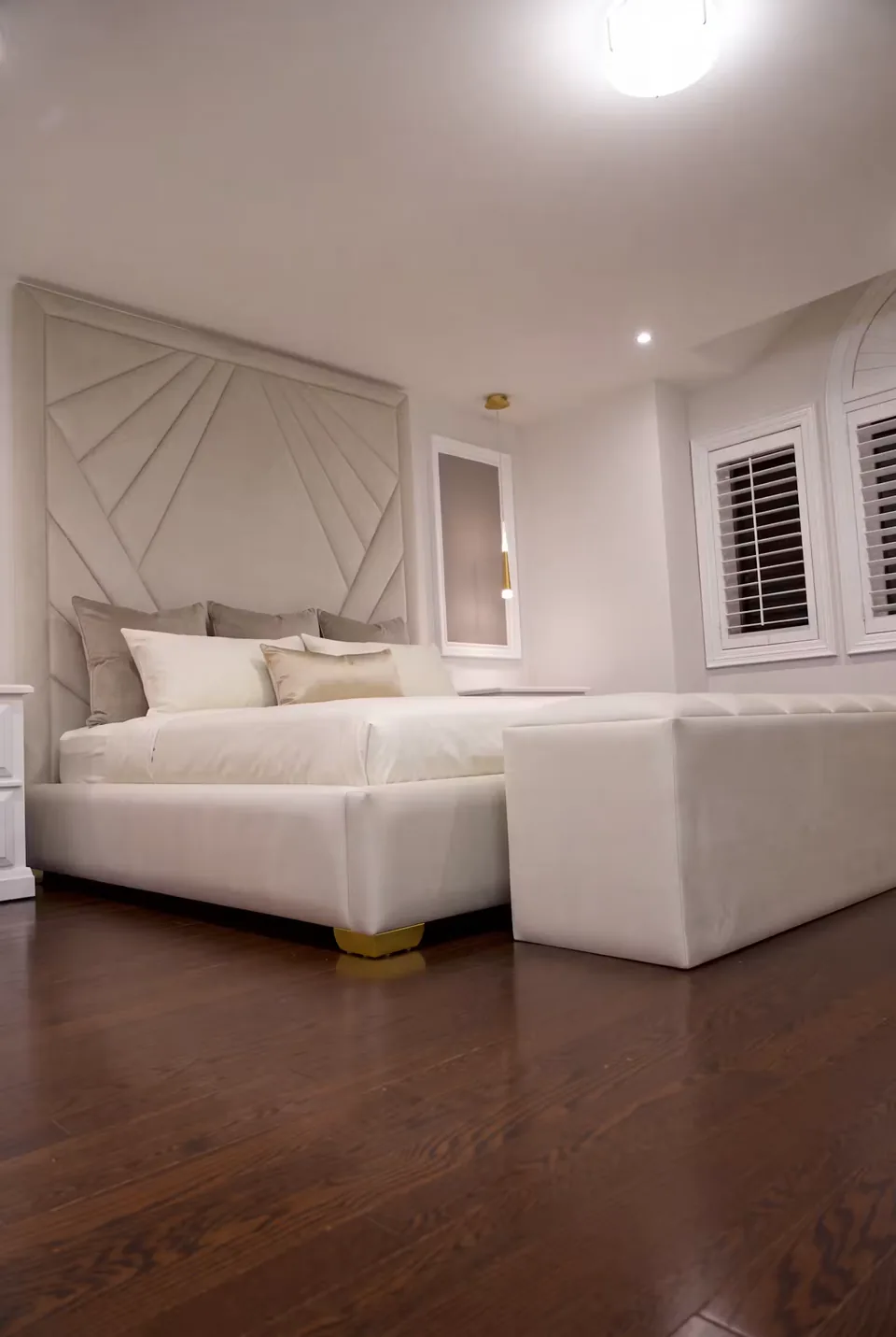 Wide room view of the cream bed and matching upholstered bench