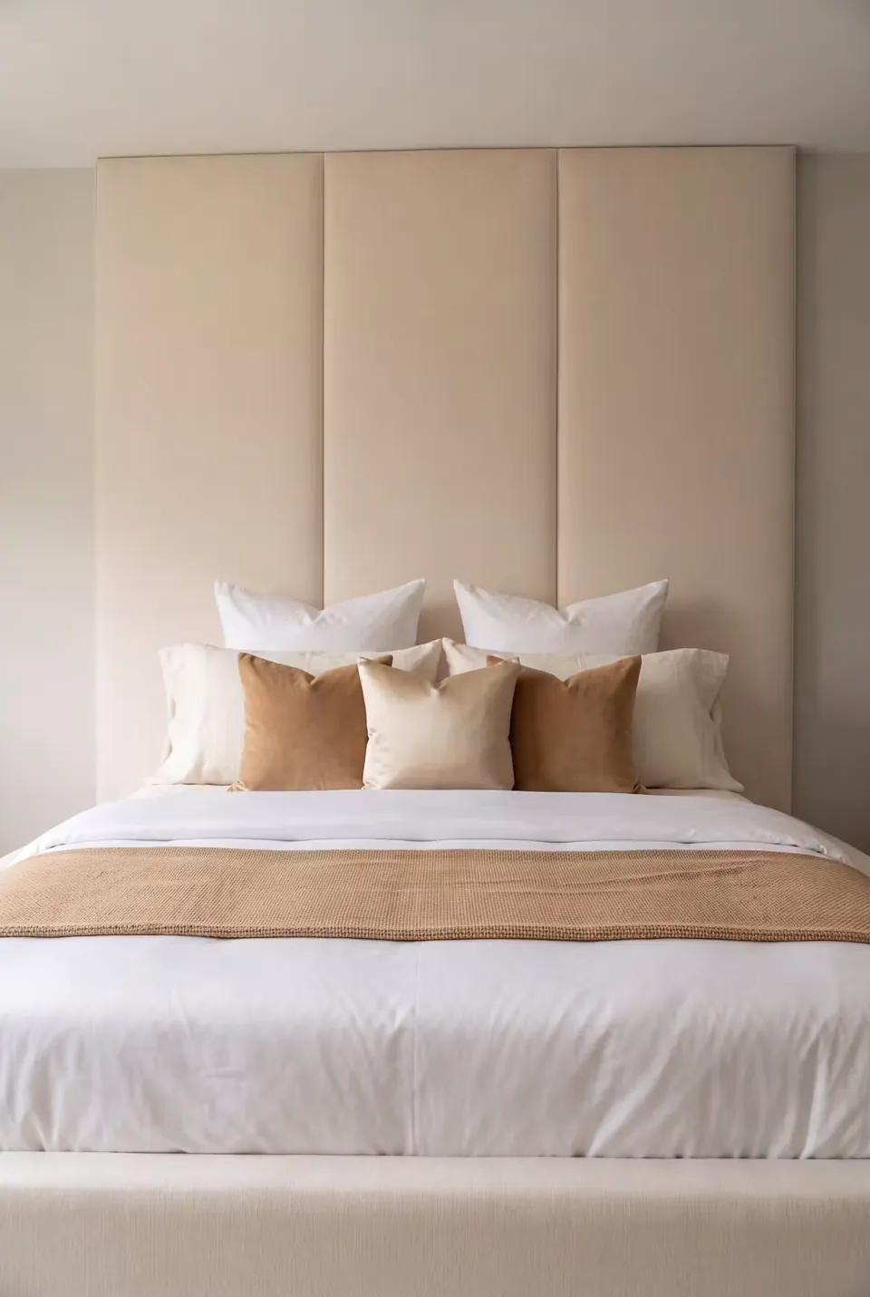 Front detail of cream wall panels and caramel cushions above white bedding.