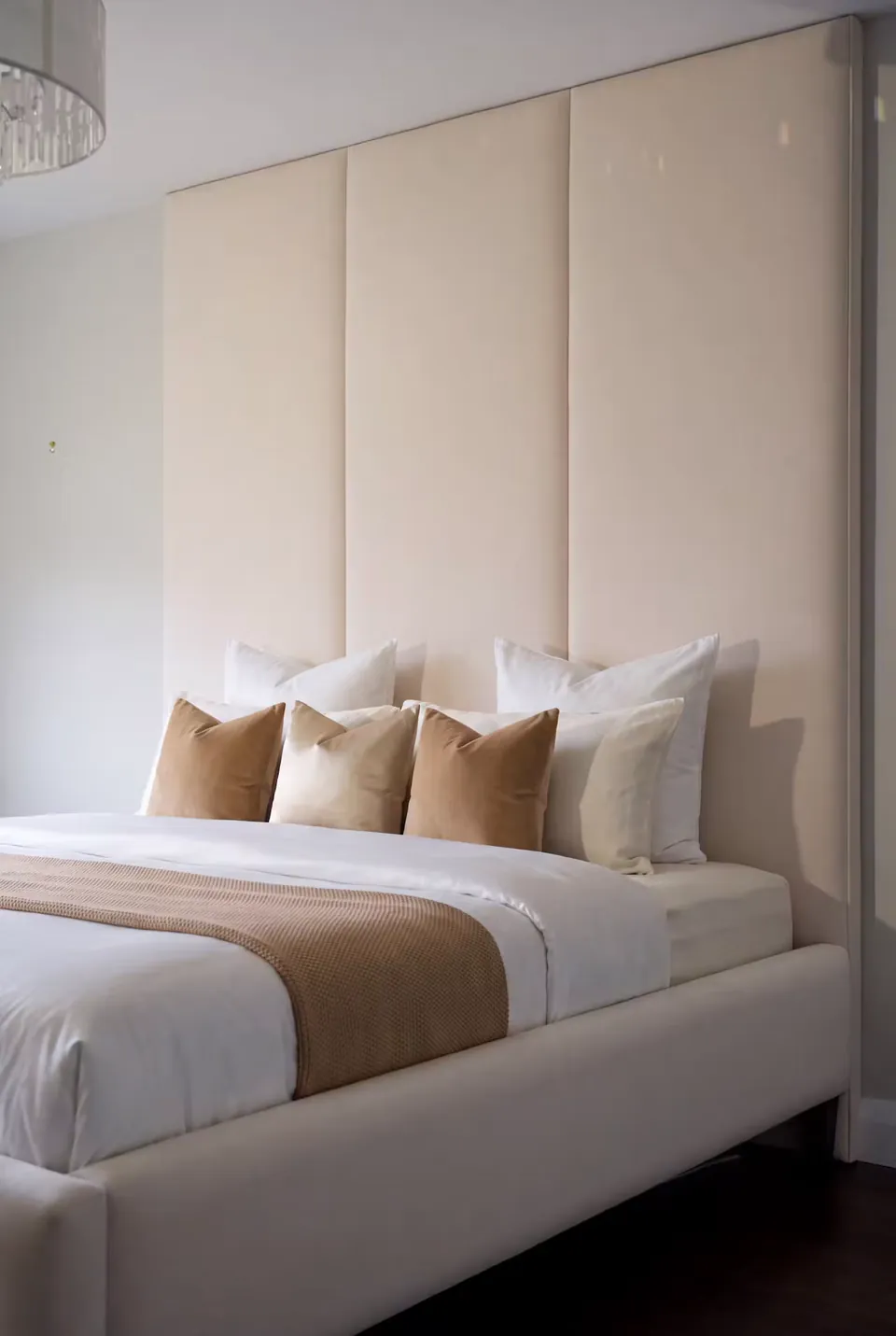 Side view of the low cream frame and broad upholstered headboard panels.