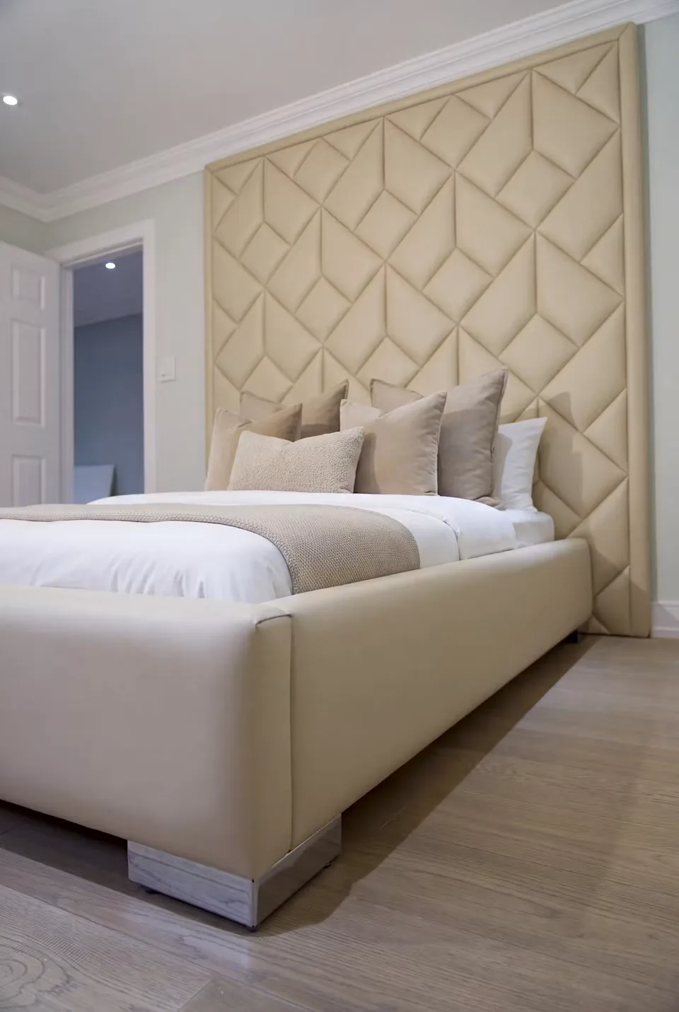 Angled view of the cream bed beneath the tall padded wall