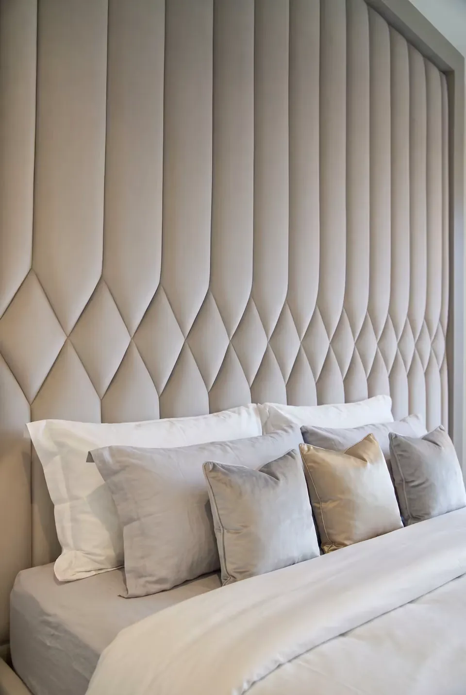 Close view of tall grey channels meeting the padded diamond band behind the pillows.