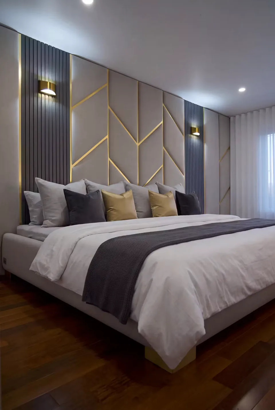 Upholstered bed below pale headboard panels with gold-toned angled lines and dark slatted sides