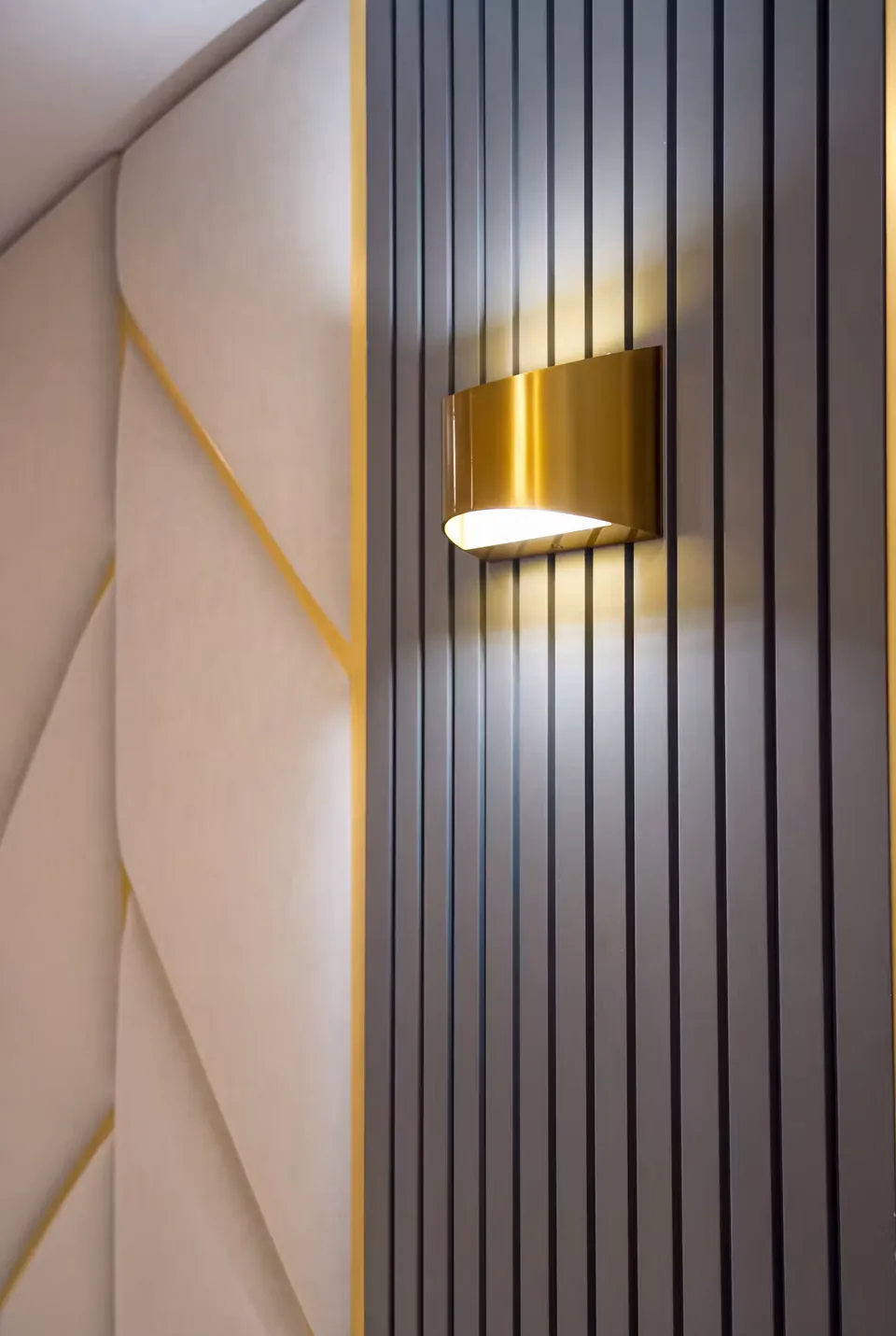 Close view of pale upholstered wall panels, gold-toned seams and a dark slatted side panel