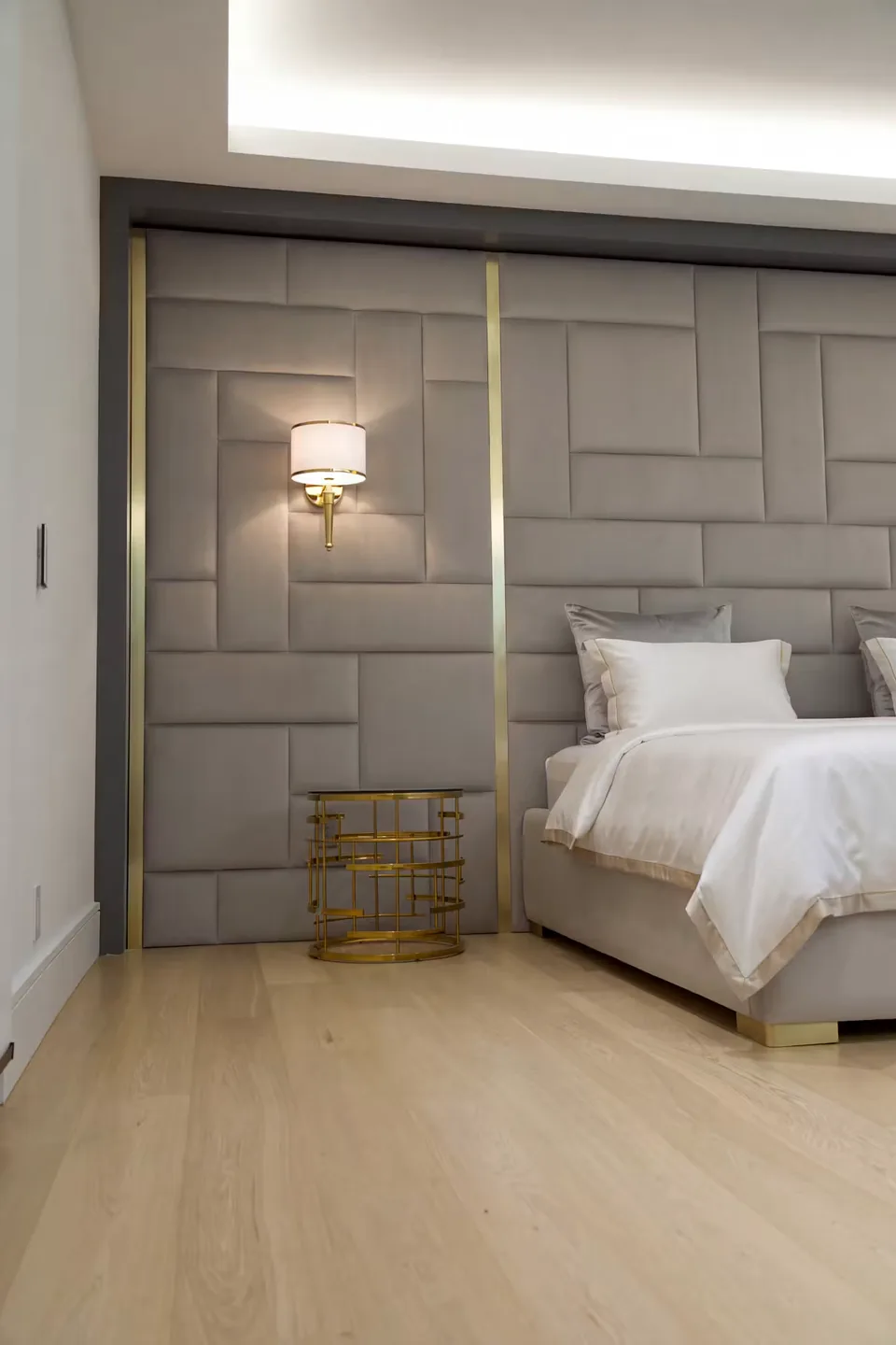 Portrait side view of the greige upholstered wall and part of the bed