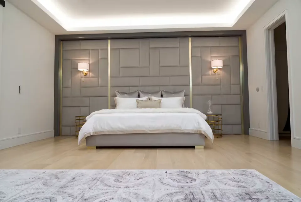 Full front room view of the greige bed beneath the rectangular block wall