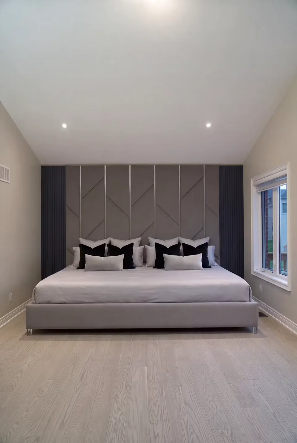 Full greige upholstered bed with branching diagonal wall panels and dark side columns
