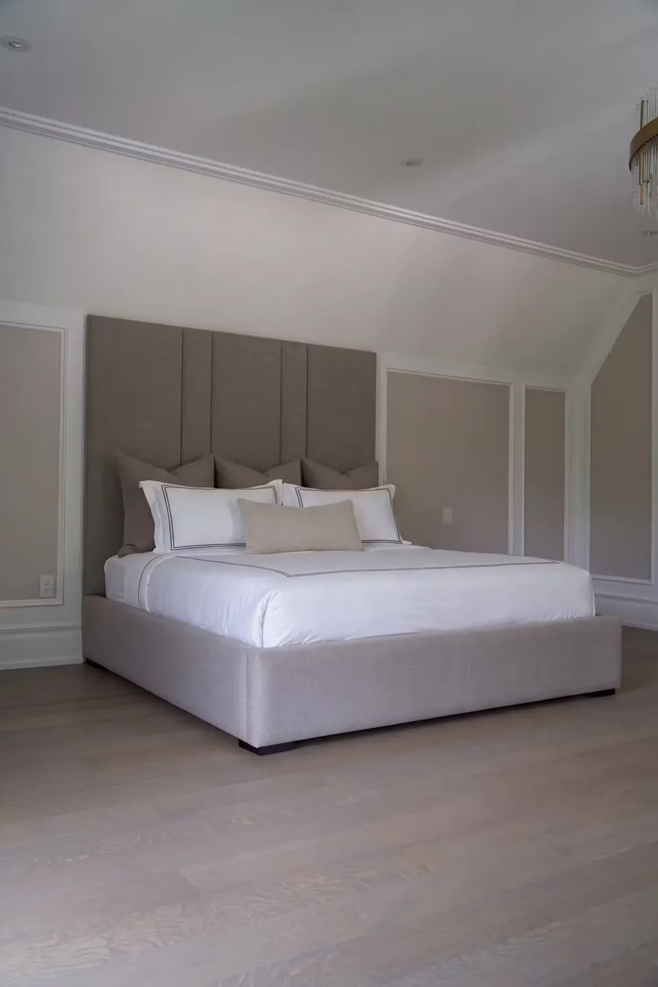 Full angled view of the greige bed and tall vertical headboard