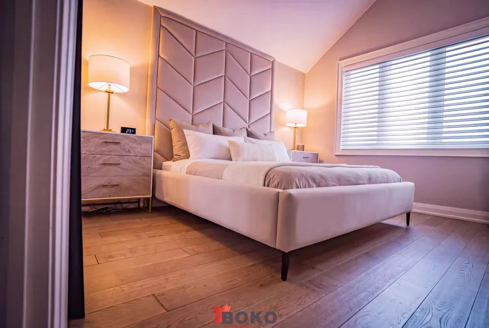 Wide angled view of the greige upholstered bed beside the window