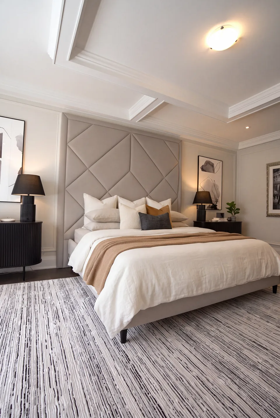 Angled view of the diamond-panel bed between dark lamps and framed artwork.