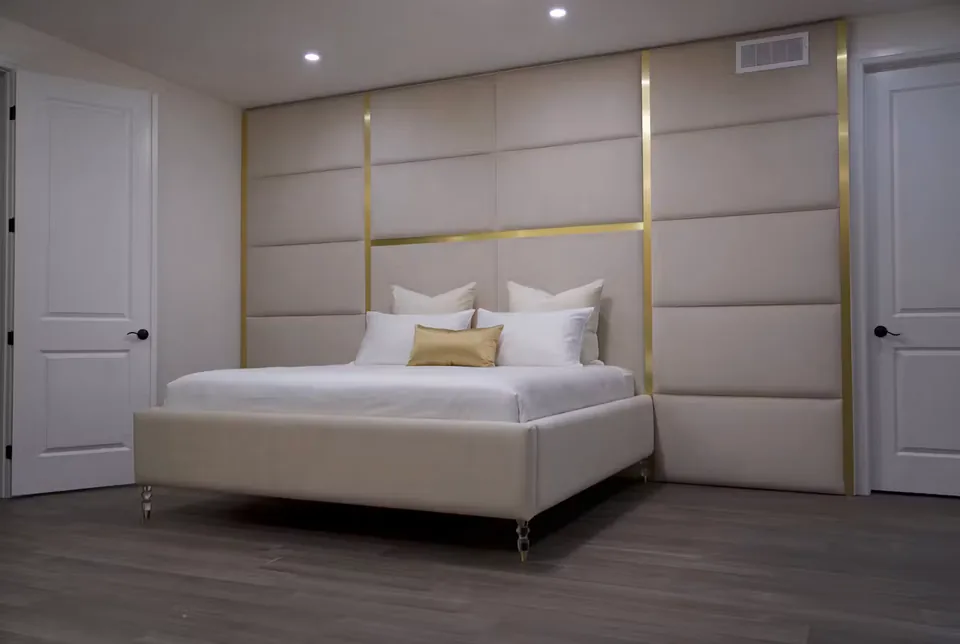Angled view of the pale bed and broad gold-edged upholstery panels