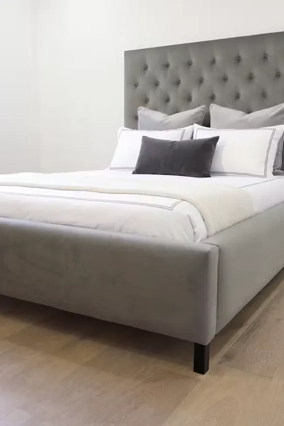 Portrait crop of the grey upholstered bed and buttoned headboard
