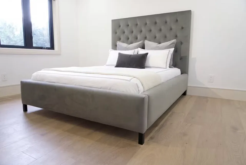 Full angled view of the grey bed with buttoned headboard and dark legs