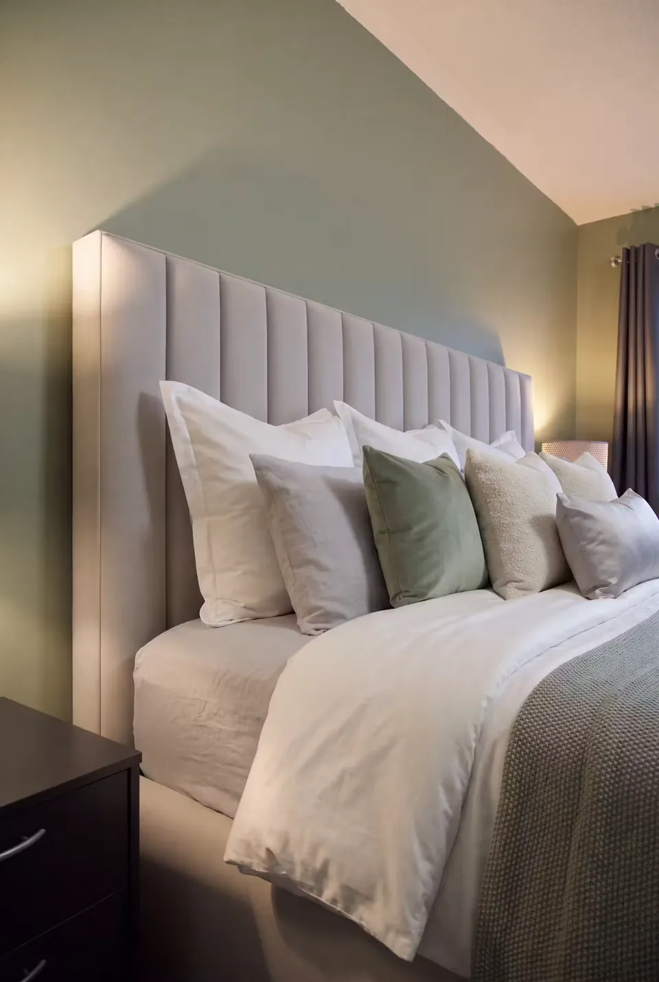 Close view of grey headboard channels with white and sage cushions.