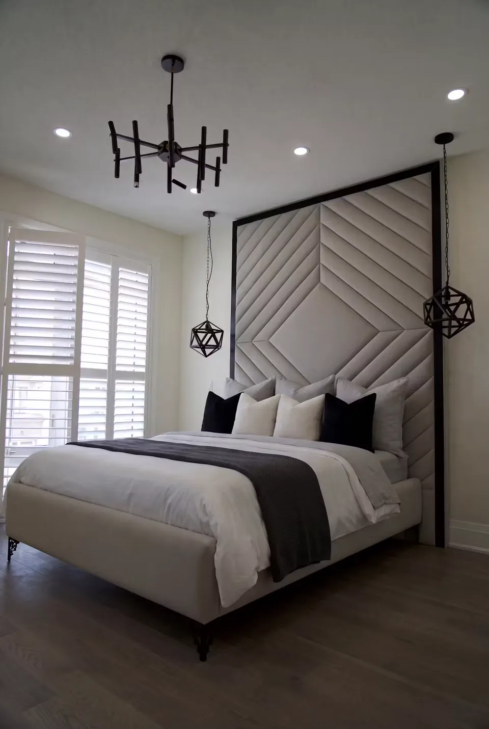 Custom grey chevron headboard with a black surround above a pale upholstered bed