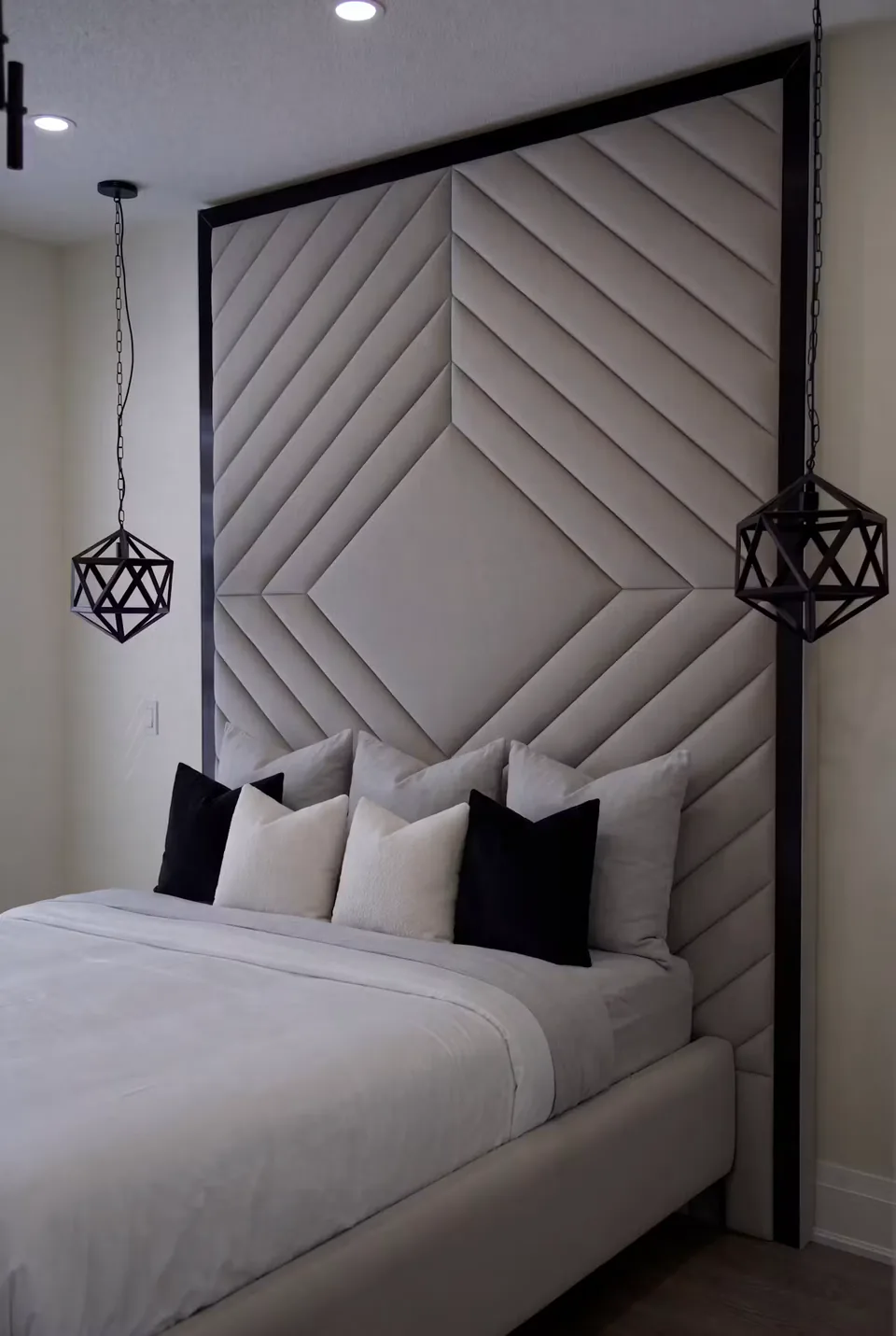 Angled view of padded grey headboard strips and a pale bed inside a black frame