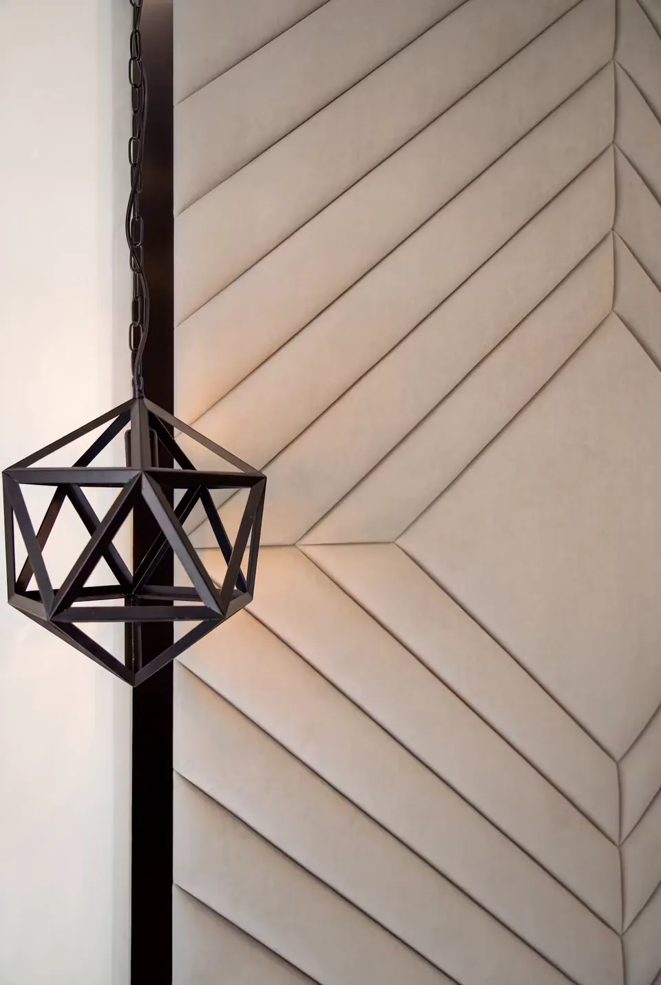 Close view of grey upholstered chevrons beside a black geometric pendant