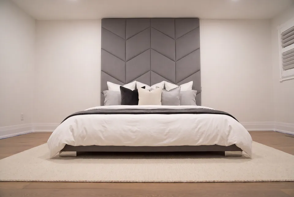 Full front view of a grey upholstered bed beneath a tall chevron headboard.