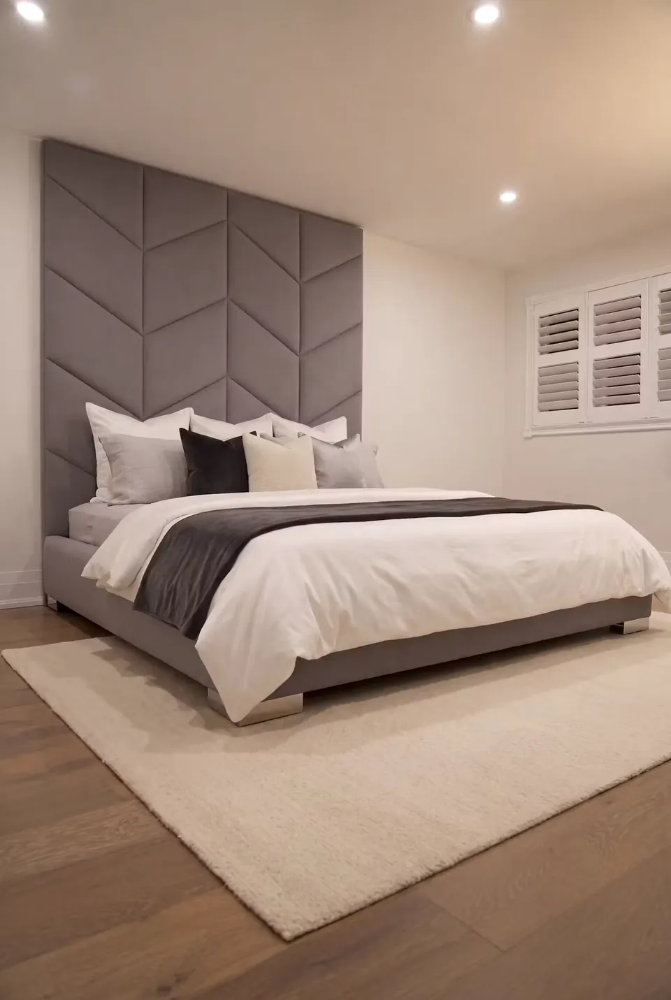 Angled view of the grey chevron bed with white bedding and a black throw.