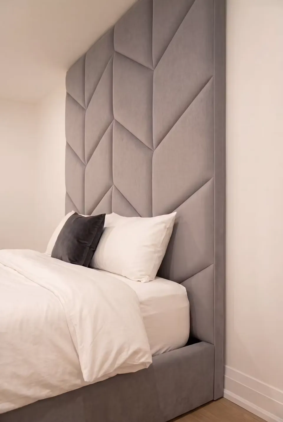 Close view of grey padded chevrons rising behind neutral pillows.