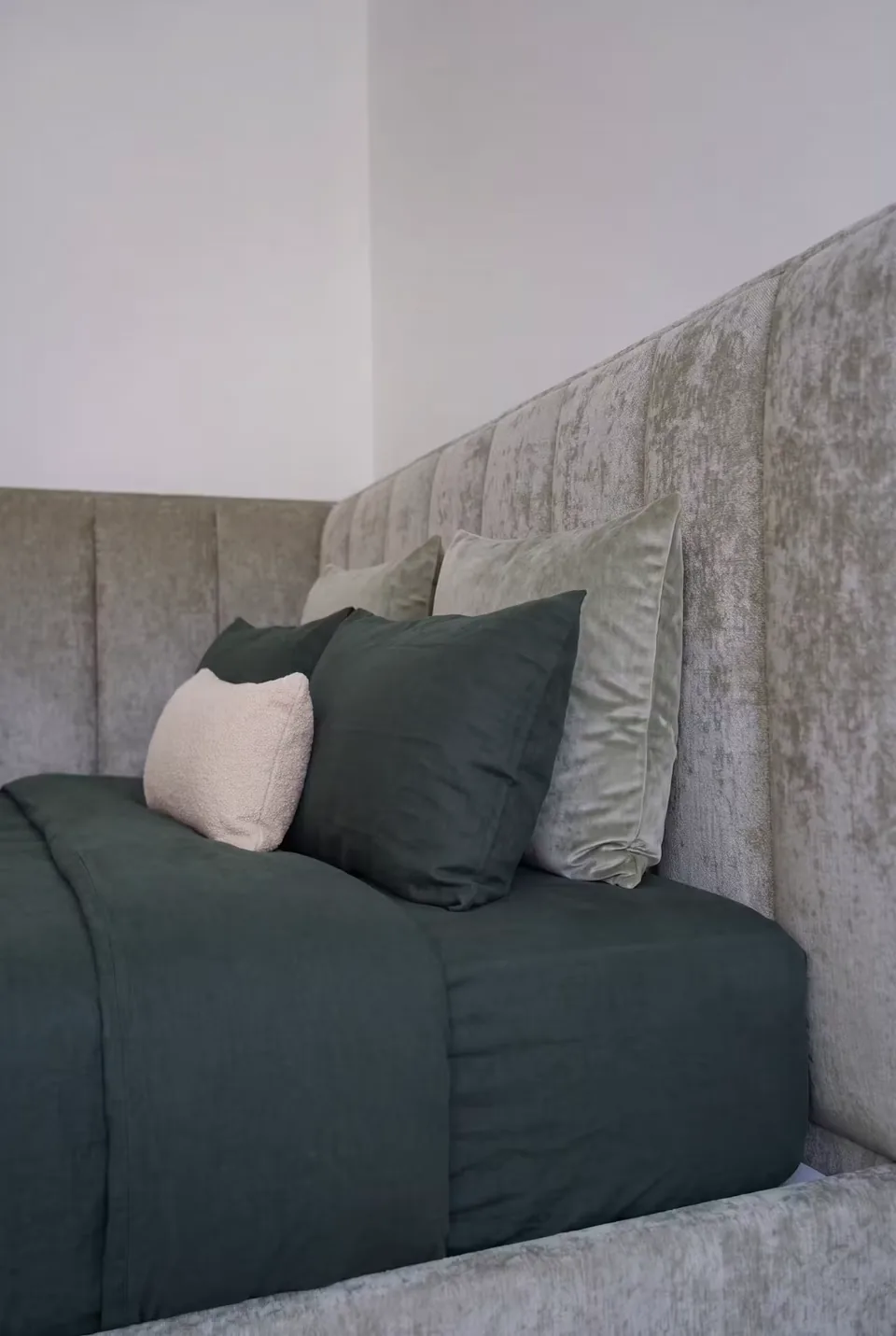 Close view of the grey padded corner and layered green cushions