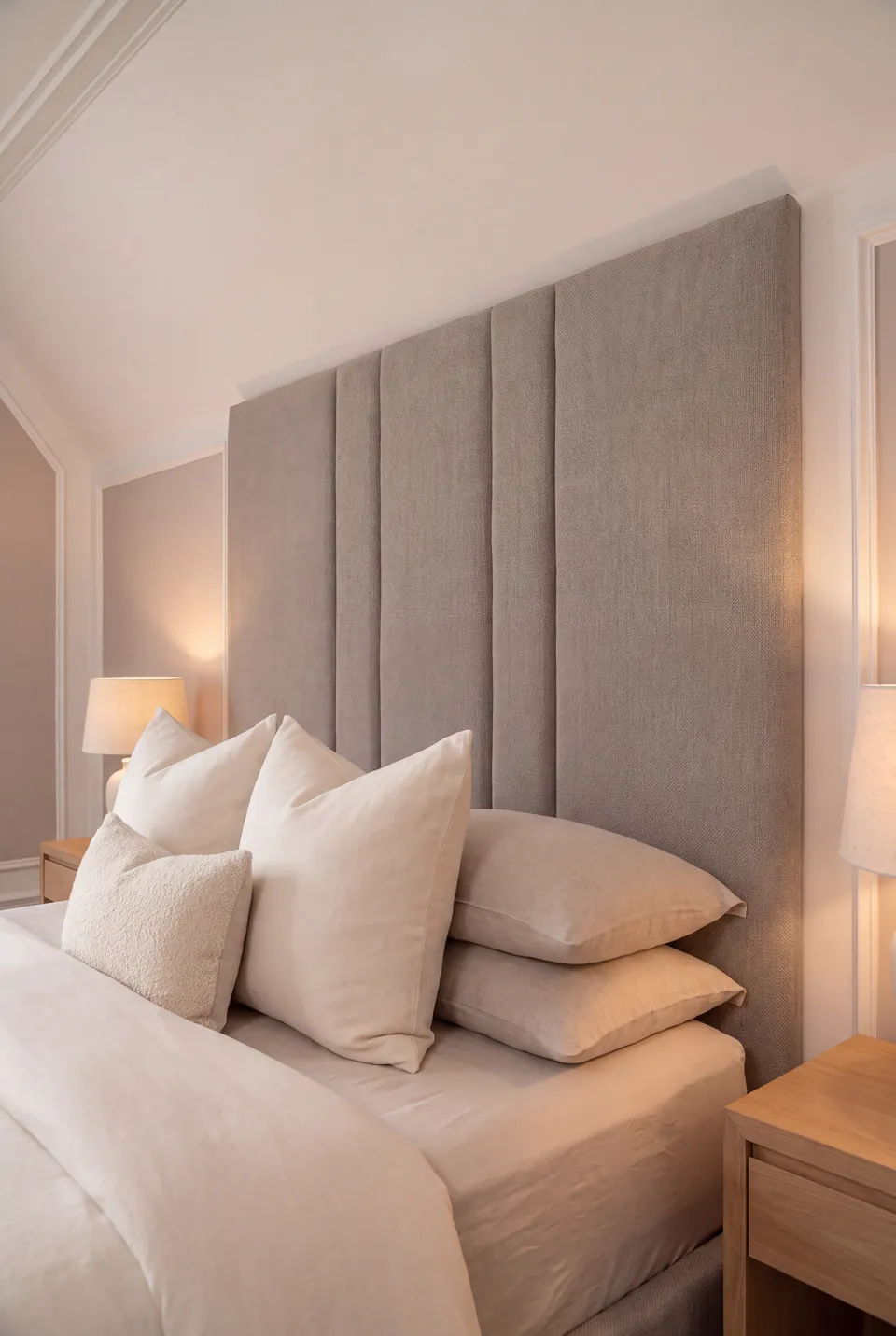 Close view of paired headboard seams and layered cream pillows.