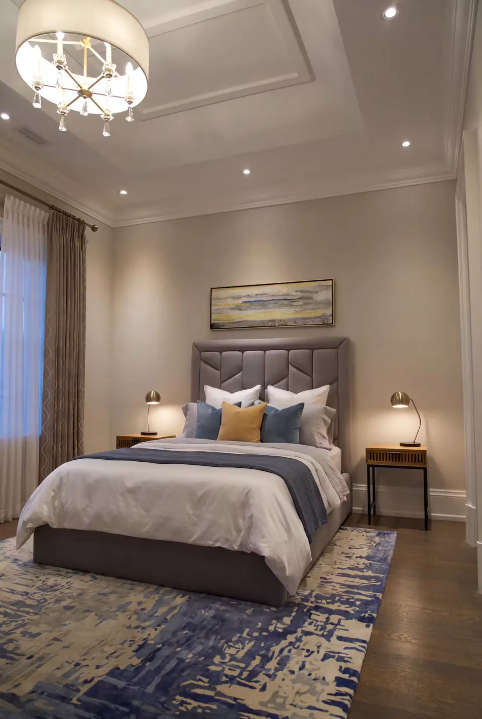 Full angled view of a grey faceted wingback bed on a blue patterned rug.
