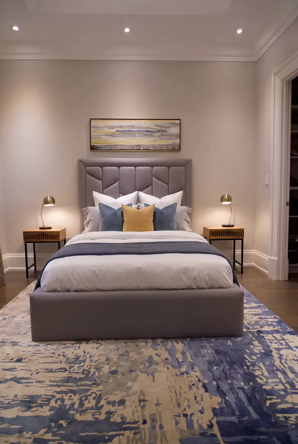 Front view of the grey wingback bed with blue and ochre cushions.