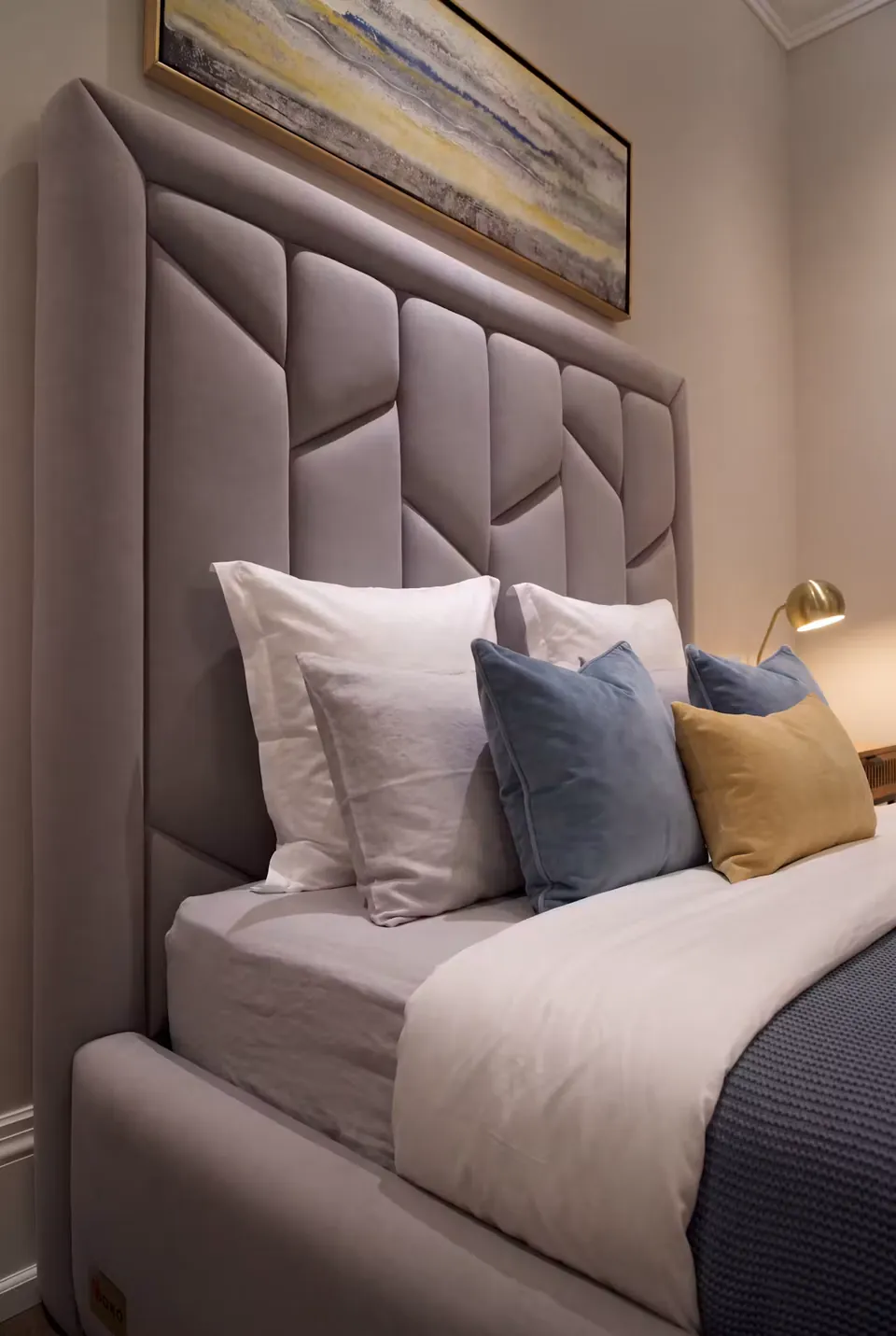 Close side view of the padded geometric headboard and enclosing grey wing.