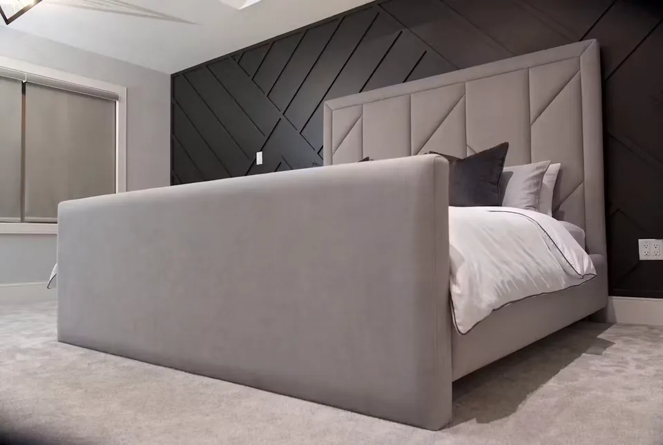 Low wide view of the grey bed and tall upholstered footboard