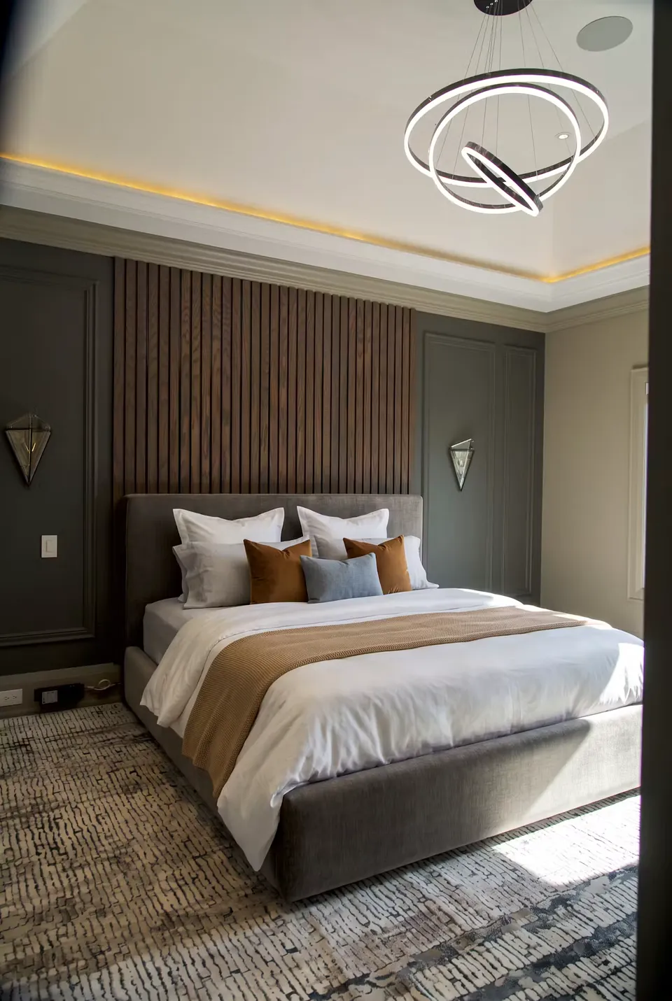 Full angled view of a grey upholstered bed against a dark wood-toned slat wall.