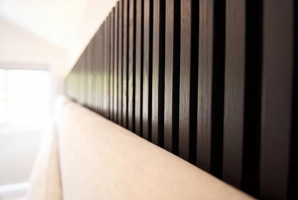 Detail of the illuminated edge above a dark slatted bedroom wall