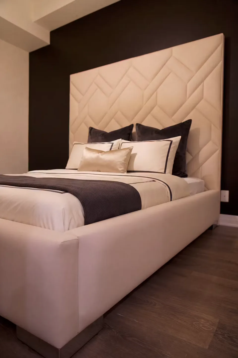 Full view of the ivory bed and tall angular headboard