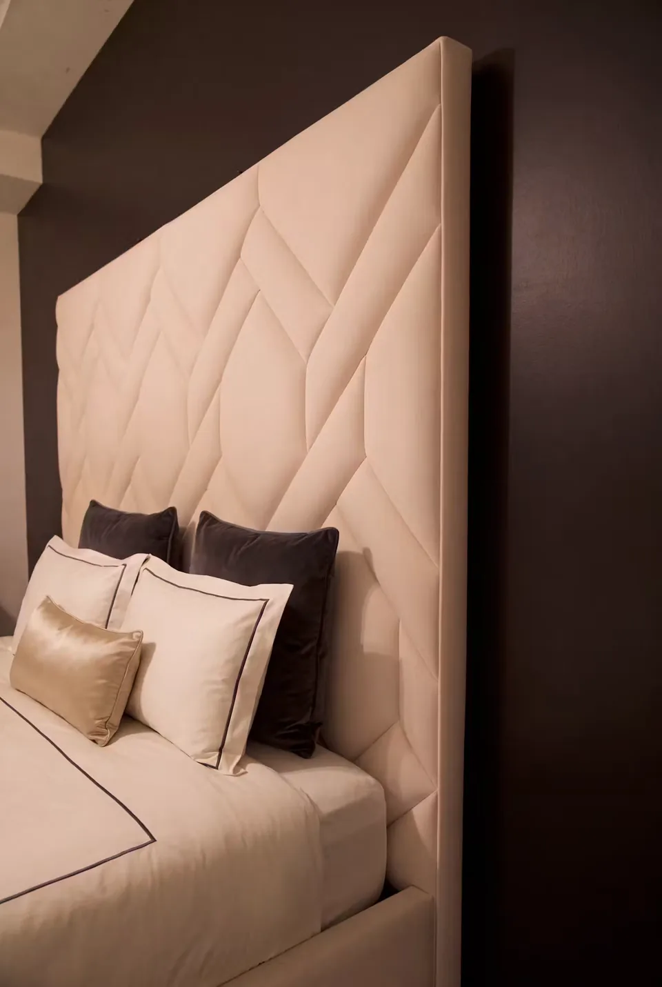 Side view of the ivory geometric headboard against a dark wall