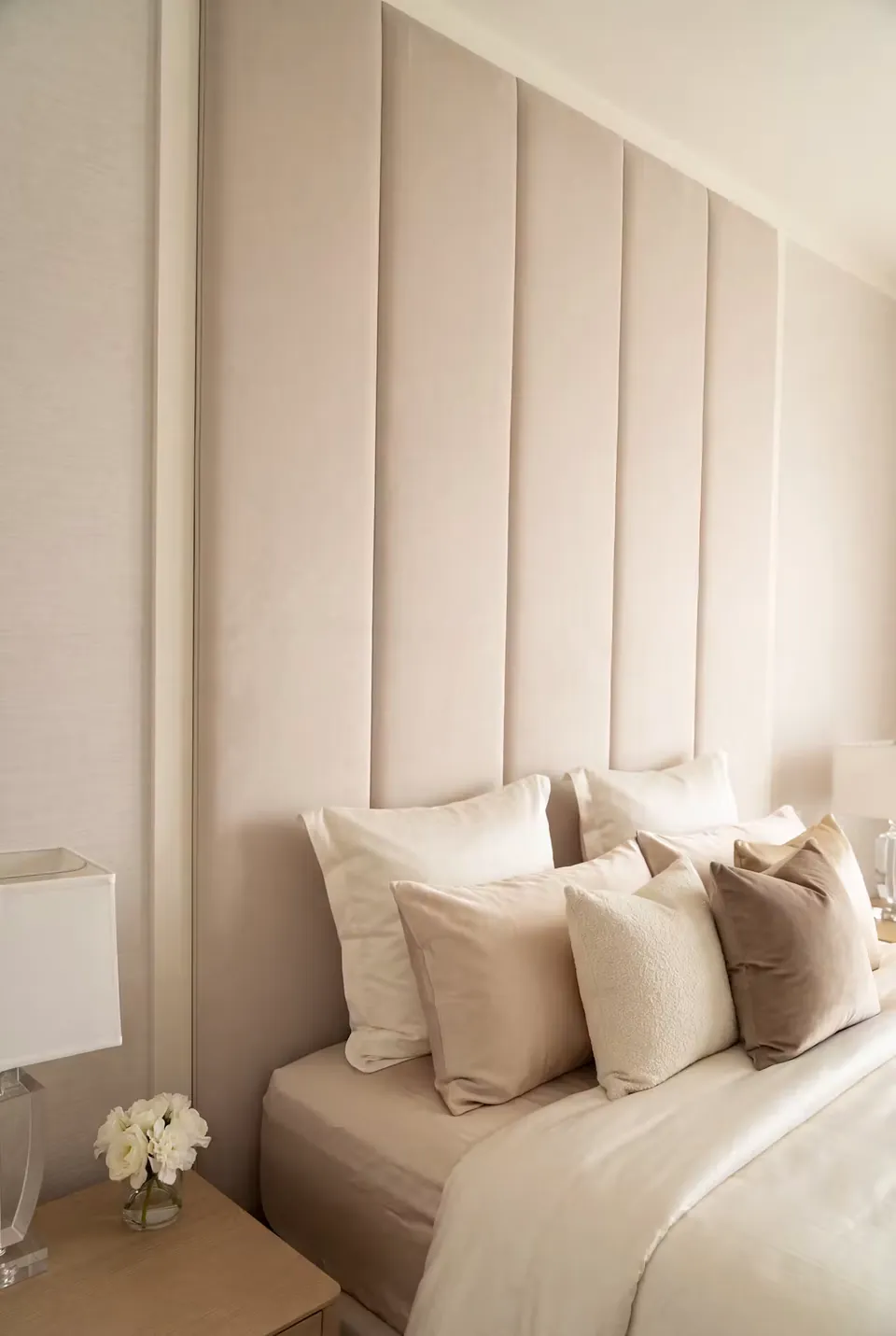 Close side view of cream pillows against tall ivory upholstered channels.