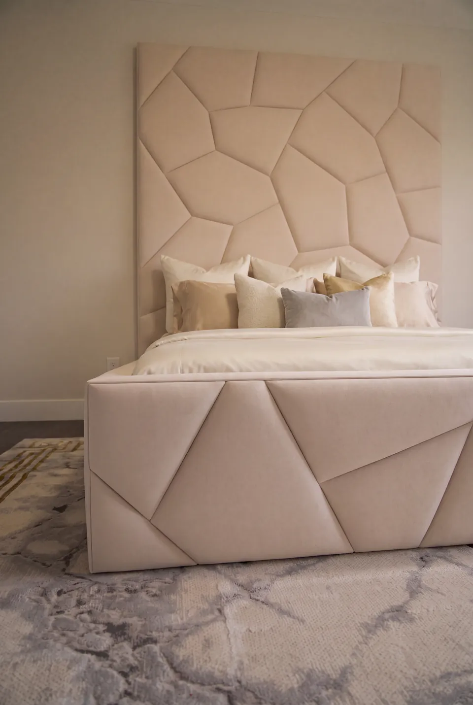 Front detail of the ivory footboard and irregular padded headboard wall.