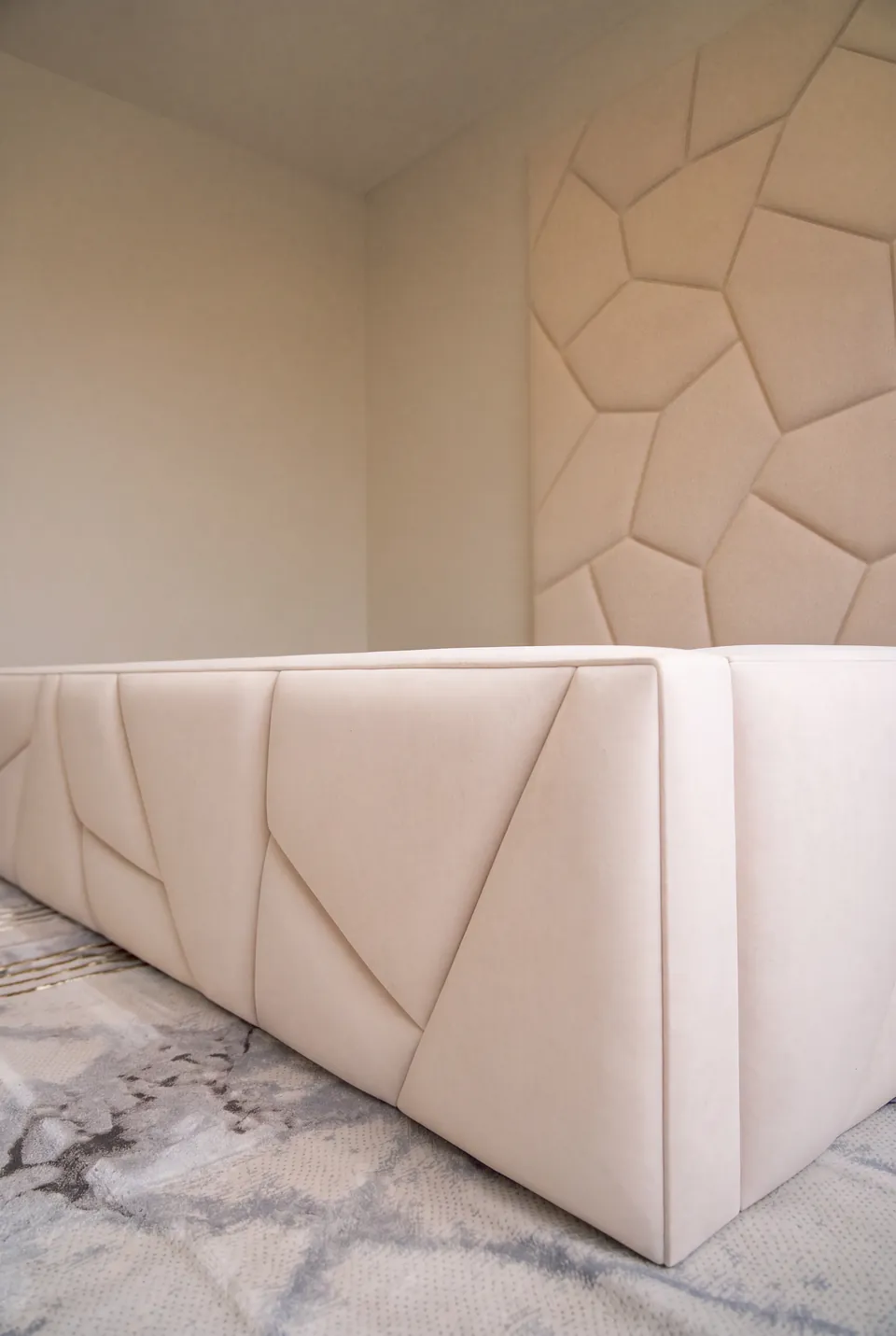 Close view of diagonal seams on the ivory upholstered bed frame.