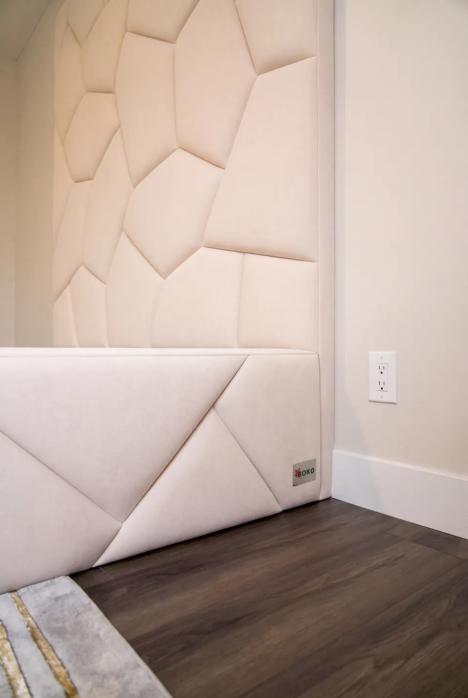 Side detail of the ivory frame beneath polygon-shaped upholstered wall panels.