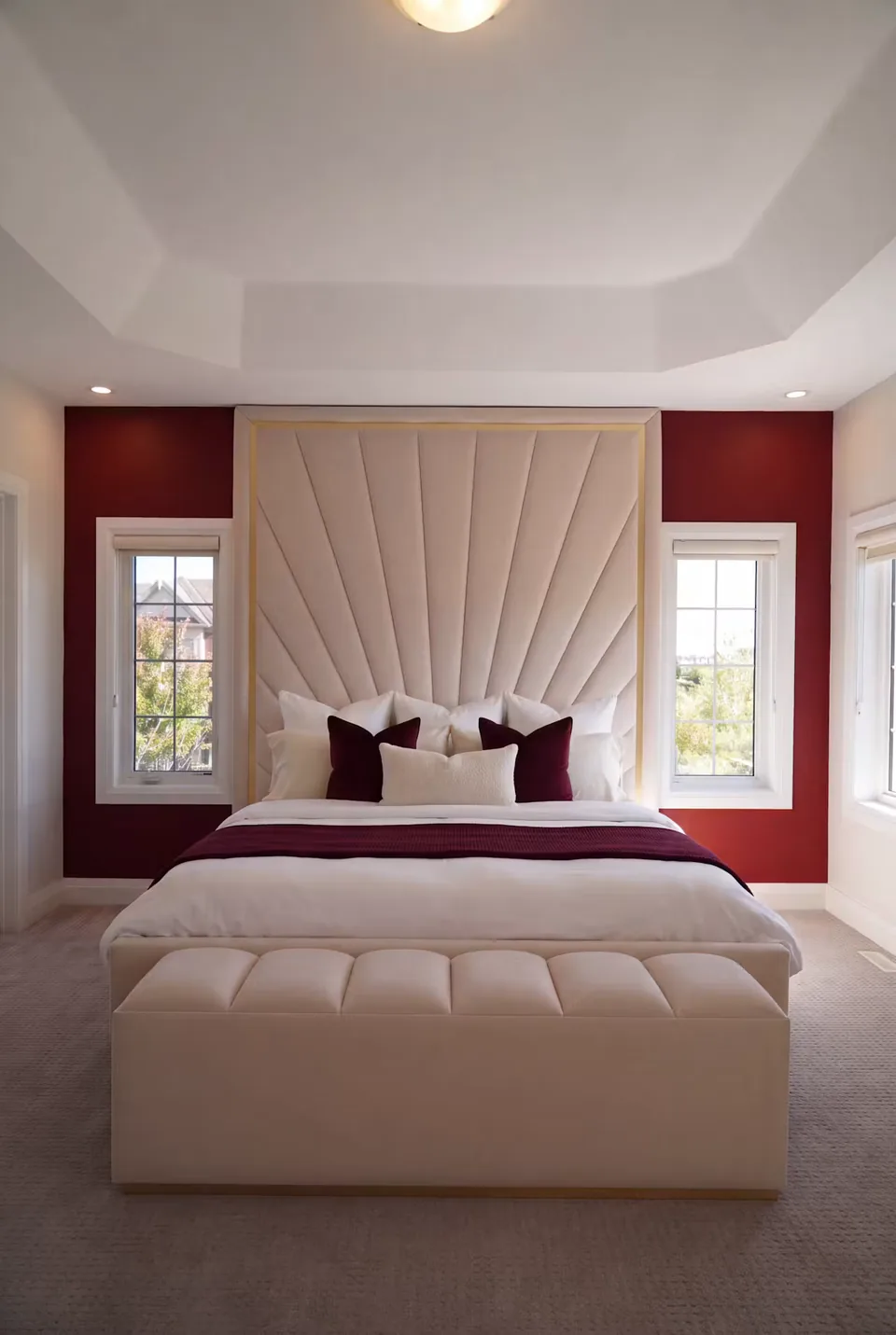 Full front view of the ivory bed and bench with fan-shaped panels against deep red wall sections.