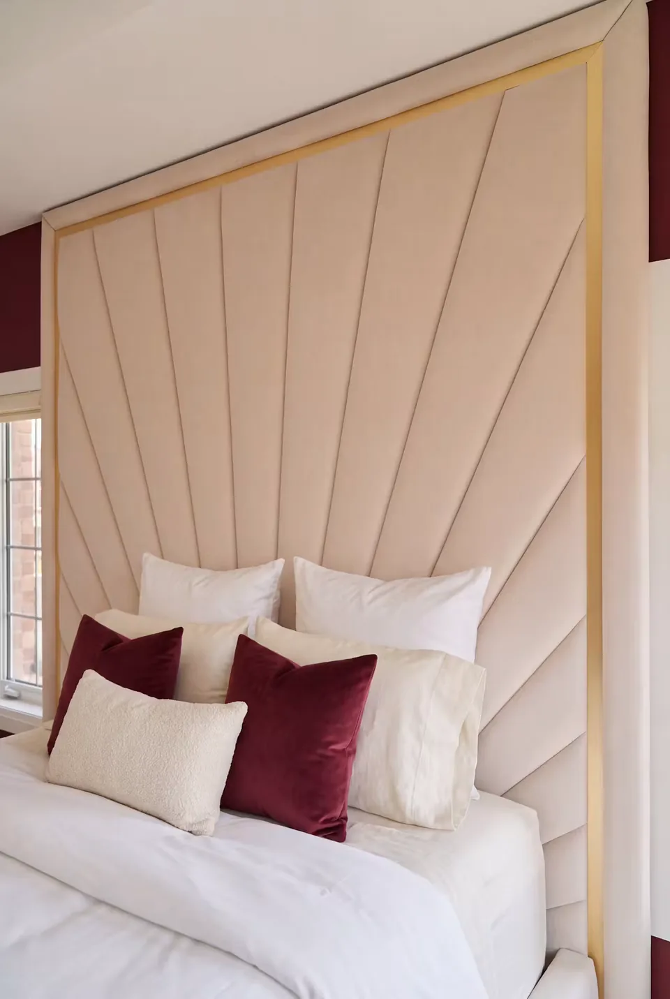Detail of ivory fan-shaped upholstered panels with gold edging behind white and burgundy cushions.