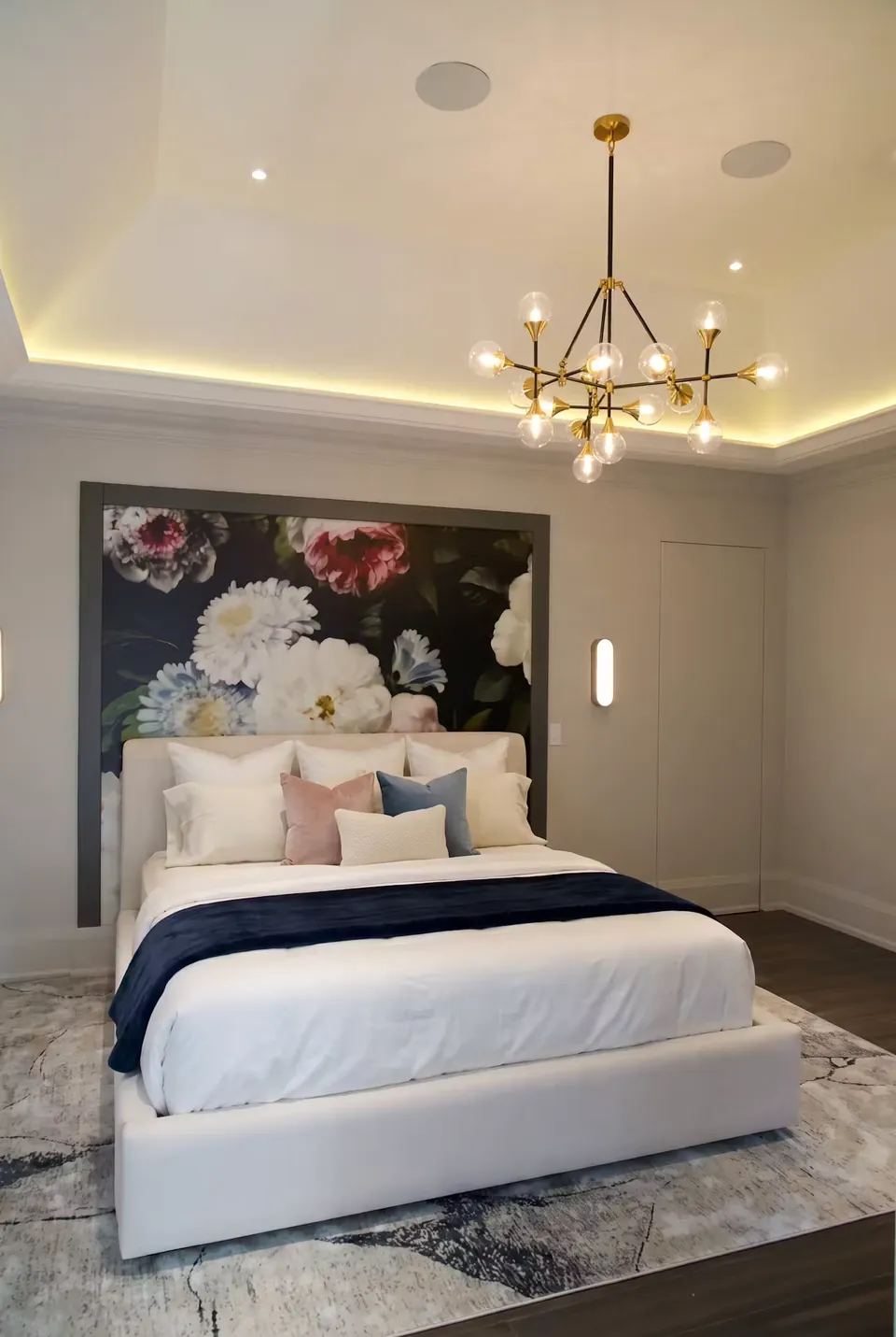 Front view of an ivory bed with a navy throw and large floral backdrop.